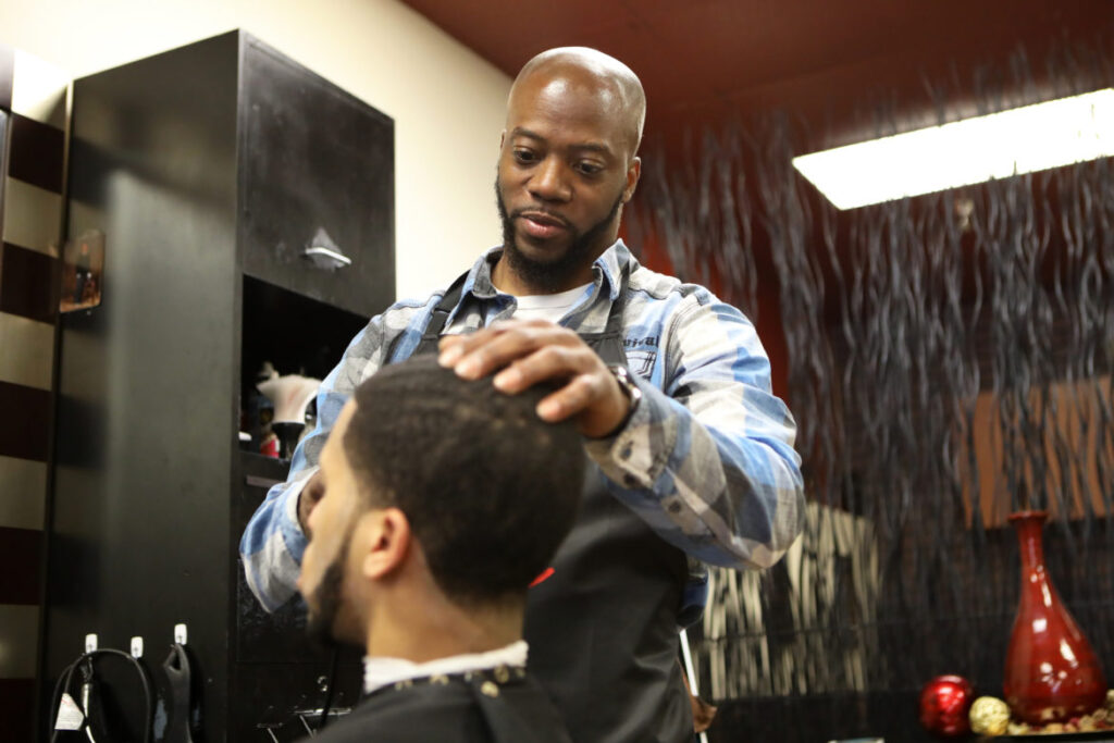 Brian Britt cuts the hair of DeUndre Moore at the Inspire Barber and Beauty Salon, which he owns, in Madison, Wis., on May 8, 2019. Britt opened the salon in 2017 and said he had difficulty finding a space to rent due to having a number of convictions on his record, including possession with intent to deliver marijuana in 2000.