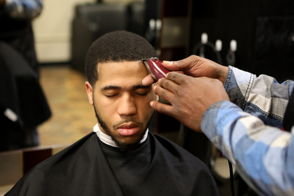 Brian Britt cuts the hair of DeUndre Moore at the Inspire Barber and Beauty Salon, which he owns, in Madison, Wis., on May 8, 2019. Britt says he spent five years in prison and has seen firsthand how challenging it is for someone with a criminal record to attend school or start a business.